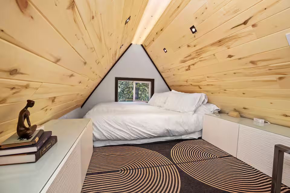 Queen bed in the A-frame loft bedroom with pine wood ceiling — nearly 30ft above the ground
