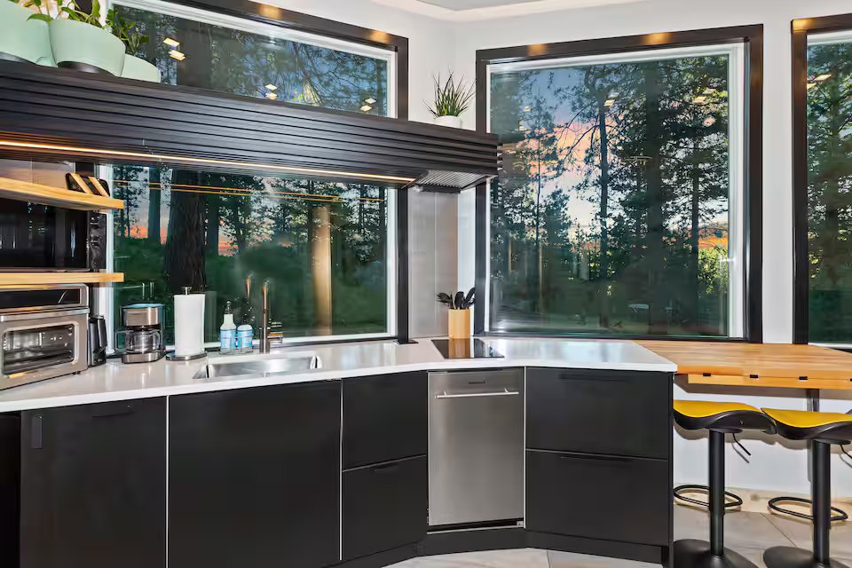 Kitchen counter detail with forest views through large windows