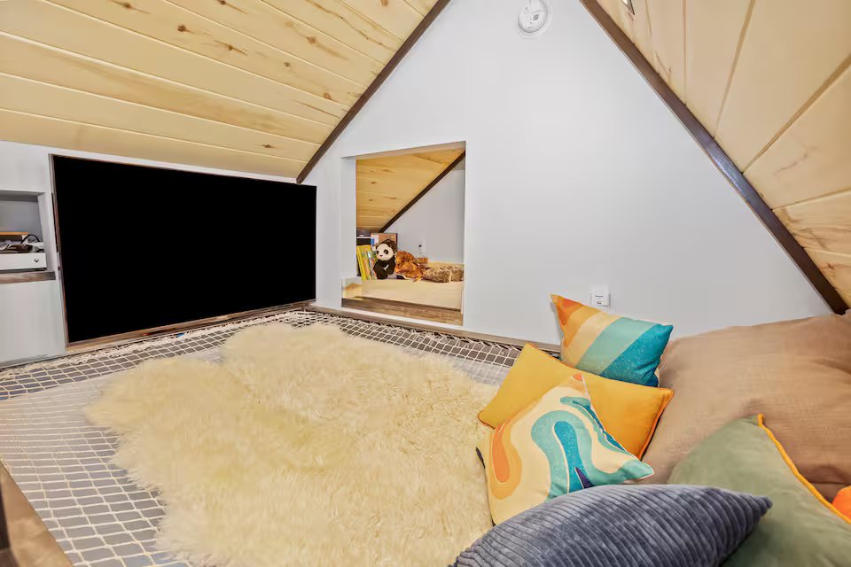 Net loft with TV, sheepskin rug, and colorful pillows — a cozy hangout spot